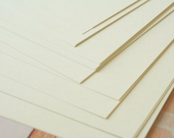 May include: A stack of off-white cardstock paper, with the edges of the sheets aligned.