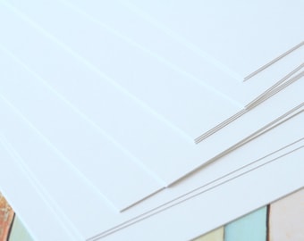 May include: A stack of white paper sheets, with the edges of the sheets slightly overlapping.