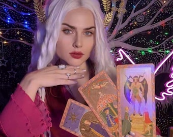 May include: A woman with white hair and a gold crown holds a spread of tarot cards. The cards are decorated with colorful illustrations and feature a variety of characters and symbols.