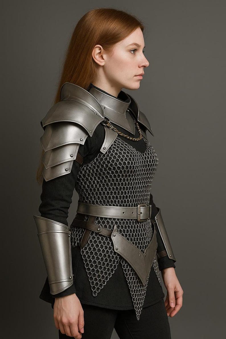 May include: A silver-colored medieval armor set, including shoulder pauldrons, a gorget, and arm guards. The armor is worn over a chainmail shirt and a leather belt. The overall design is detailed and realistic, suitable for cosplay or historical reenactment.