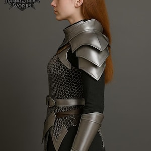 May include: A silver-colored medieval armor set, including shoulder pauldrons, arm guards, and a chest piece with a chainmail design. The armor is worn over a black garment. The RegalSteel Works logo is visible.