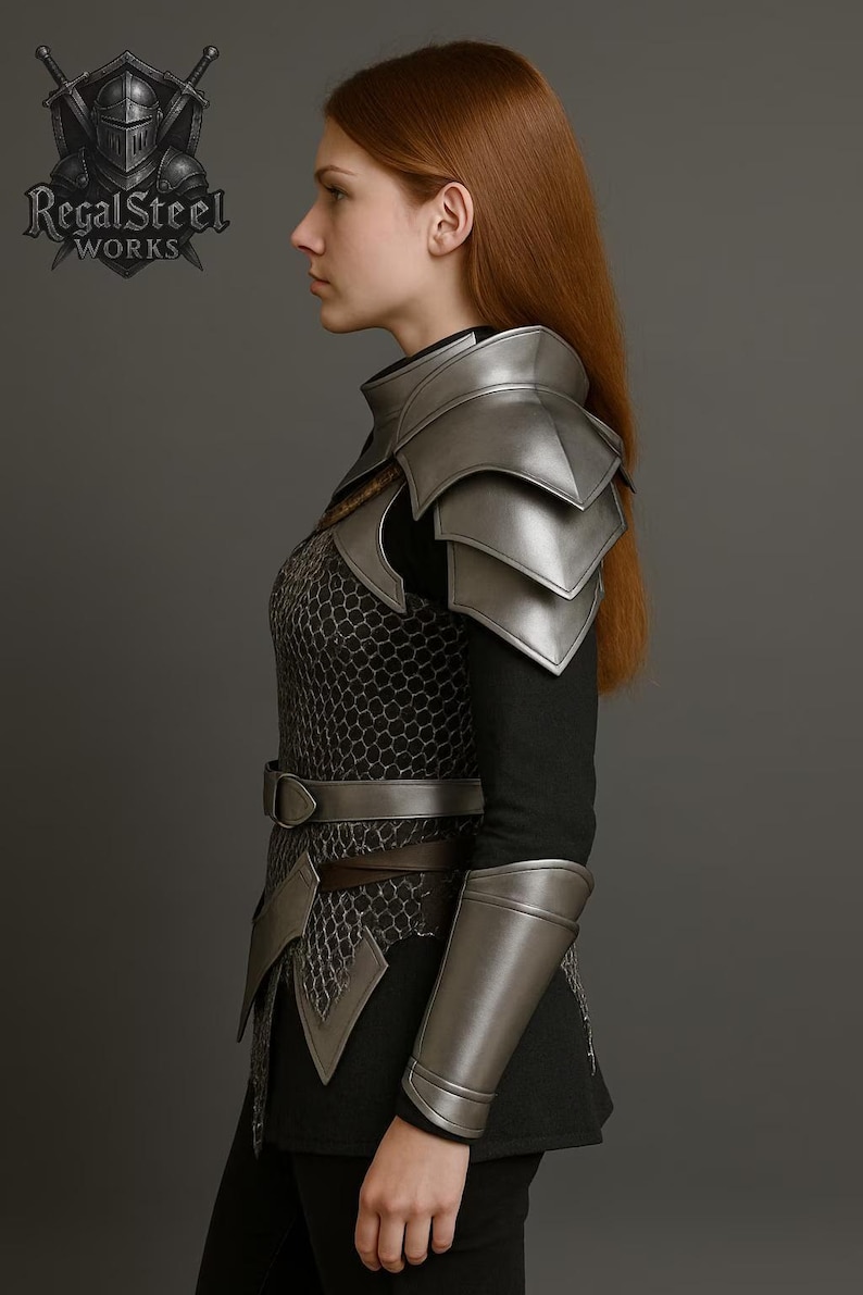 May include: A silver-colored medieval armor set, including shoulder pauldrons, arm guards, and a chest piece with a chainmail design. The armor is worn over a black garment. The RegalSteel Works logo is visible.