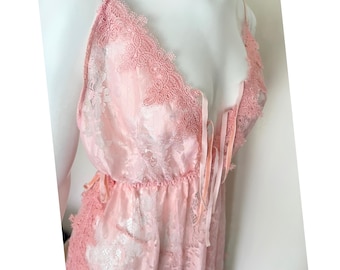 Könnte beinhalten: Ein zartes rosa Spitzen-Oberteil für Dessous mit verstellbaren Trägern und einem tiefen Ausschnitt. Das Oberteil ist aus weichem, durchsichtigem Stoff gefertigt und mit aufwendigen floralen Spitzendetails verziert.