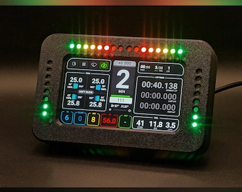 Puede incluir: Una pantalla digital rectangular negra que muestra varios datos de carrera, incluyendo tiempos de vuelta y velocidad. El dispositivo tiene luces LED verdes y rojas en los bordes y en la parte superior. La pantalla muestra números y texto, incluyendo "SOFT SLICK".