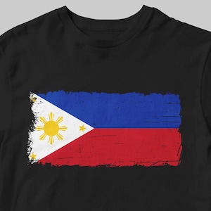 May include: A black t-shirt with a distressed, faded image of the Philippine flag. The flag is red, white, and blue with a yellow sun and three stars.