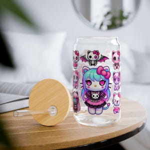 May include: A clear glass can with a pink and black design featuring a cartoon character with a skull and crossbones. The can has a bamboo lid with a hole for a straw. "Killev" is written on the character's dress.