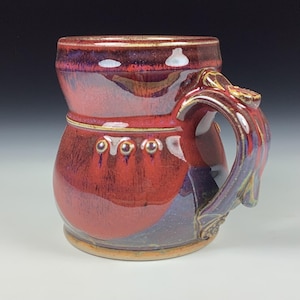 May include: A white ceramic mug with a black handle and the text "But First, Coffee" in a handwritten style. The mug is on a white surface. The mug is approximately 4 inches tall.