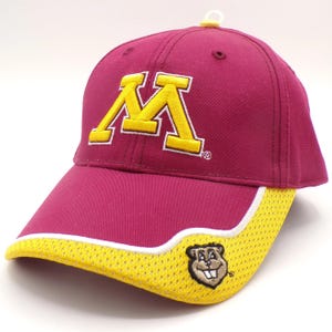 Puede incluir: Una gorra de béisbol granate con un logotipo de M en bloque bordado en amarillo en la parte delantera. La visera curva tiene una superposición de malla amarilla con un borde blanco y un pequeño gráfico de mascota gopher bordado a la derecha.