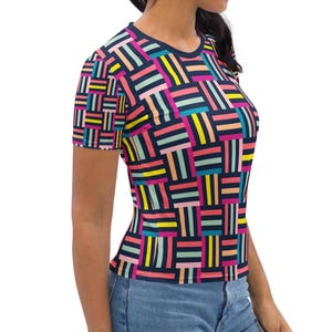 Peut inclure: Un t-shirt à manches courtes pour femme avec un motif géométrique dans des tons de rose, jaune, bleu et vert sur un fond bleu marine.