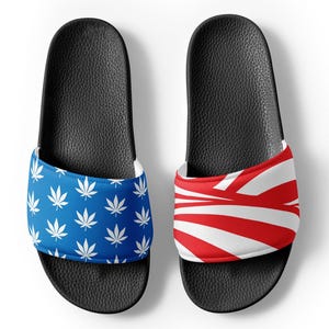 May include: Pair of black slide sandals with a white and blue marijuana leaf pattern on one sandal and a white and red striped pattern on the other sandal.