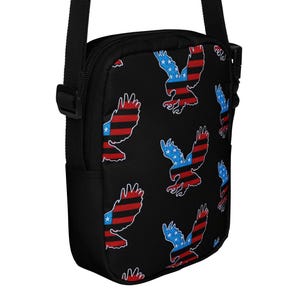 May include: Black crossbody bag with a repeating pattern of red, white, and blue eagles with American flag designs.