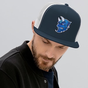 May include: A navy blue and white trucker hat with a blue and white demon face graphic. The demon has horns and a fierce expression.