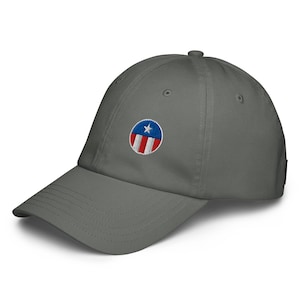May include: A gray baseball cap with a curved brim. The cap features a circular embroidered patch with a blue circle, a white star, and red and white stripes, reminiscent of a flag.