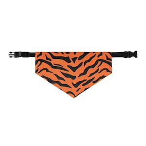 May include: Orange and black tiger stripe pet bandana with a black adjustable buckle closure. The bandana is triangular in shape and made of a lightweight fabric. The black stripes are irregular and mimic a tiger's pattern.