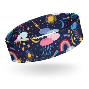 May include: A navy blue headband featuring a colorful pattern of suns, moons, rainbows, clouds, stars, and raindrops. The design includes yellow, pink, blue, and rainbow colors. This accessory is suitable for various activities.