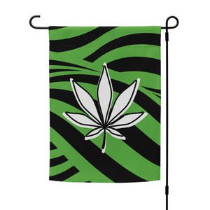 Könnte beinhalten: Grüne und schwarze Gartenflagge mit einem weißen Marihuana-Blatt-Design. Die Flagge hat ein Zebra-ähnliches Muster.