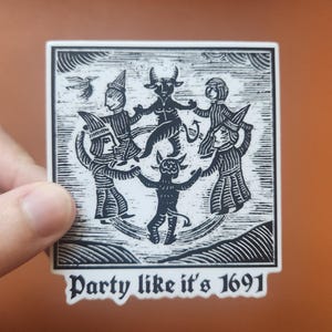 Op de afbeelding: Een vierkante sticker met een zwart-wit illustratie van dansende figuren, waaronder een gehoornde demon en mensen in gewaden en hoeden. De tekst "Party like it's 1691" staat onderaan.