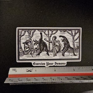 May include: Black and white sticker with a woodcut-style illustration of figures interacting with demonic creatures. The text "Exercise Your Demons" is at the bottom. The sticker is approximately 4 inches long.
