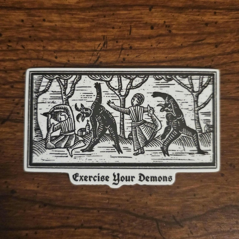 May include: A black and white sticker with a medieval-style illustration of figures interacting with demonic creatures in a forest setting. The text "Exercise Your Demons" is at the bottom of the sticker.