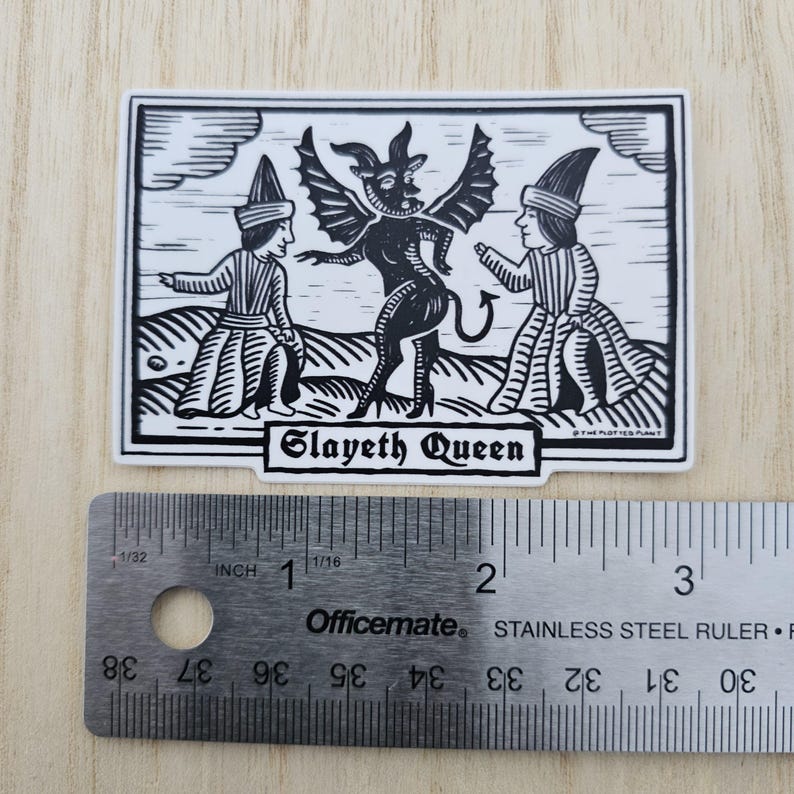 May include: Black and white sticker featuring a stylized illustration of a horned demon with bat wings, flanked by two figures in medieval attire. The text "Slayeth Queen" is displayed below the central image. The sticker is approximately 3 inches long.