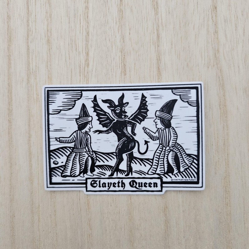 May include: Black and white sticker featuring a devil-like figure with wings, horns, and a tail, flanked by two figures in hats and robes. The text "Slayeth Queen" is displayed below the central image. The sticker has a white border.
