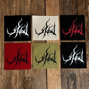 May include: Six square patches in various colors, including black, red, and beige, each featuring a stylized white or black graphic design. The patches are arranged on a wooden surface, showcasing a variety of color combinations.