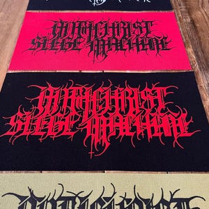 Könnte beinhalten: Eine Sammlung von Stoffaufnähern mit dem Text "Antichrist Siege Machine" in einer gotischen Schriftart. Die Aufnäher sind in verschiedenen Farben erhältlich, darunter Schwarz, Rot und Grau. Die Aufnäher sind rechteckig und wahrscheinlich für Kleidung oder Accessoires.