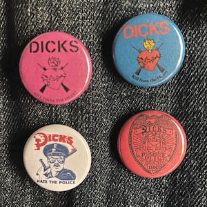 Może przedstawiać: Cztery okrągłe przypinki z napisem "DICKS" w różnych czcionkach. Przypinki są różowe, niebieskie, białe i czerwone. Każda przypinka ma inną grafikę, w tym serce, policjanta i odznakę policyjną.
