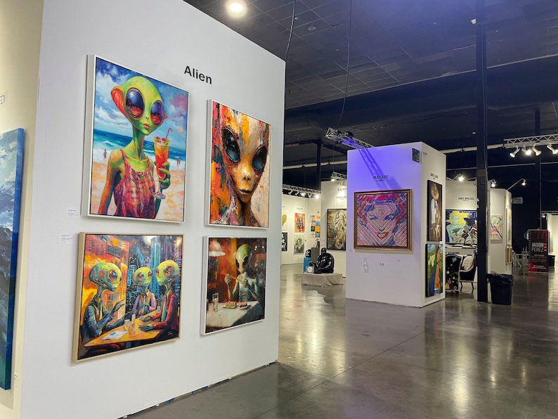 May include: An art gallery featuring framed paintings with alien themes. The paintings depict aliens in various settings, including a beach and a restaurant. The word "Alien" is displayed on the wall. Other artwork is visible in the background.