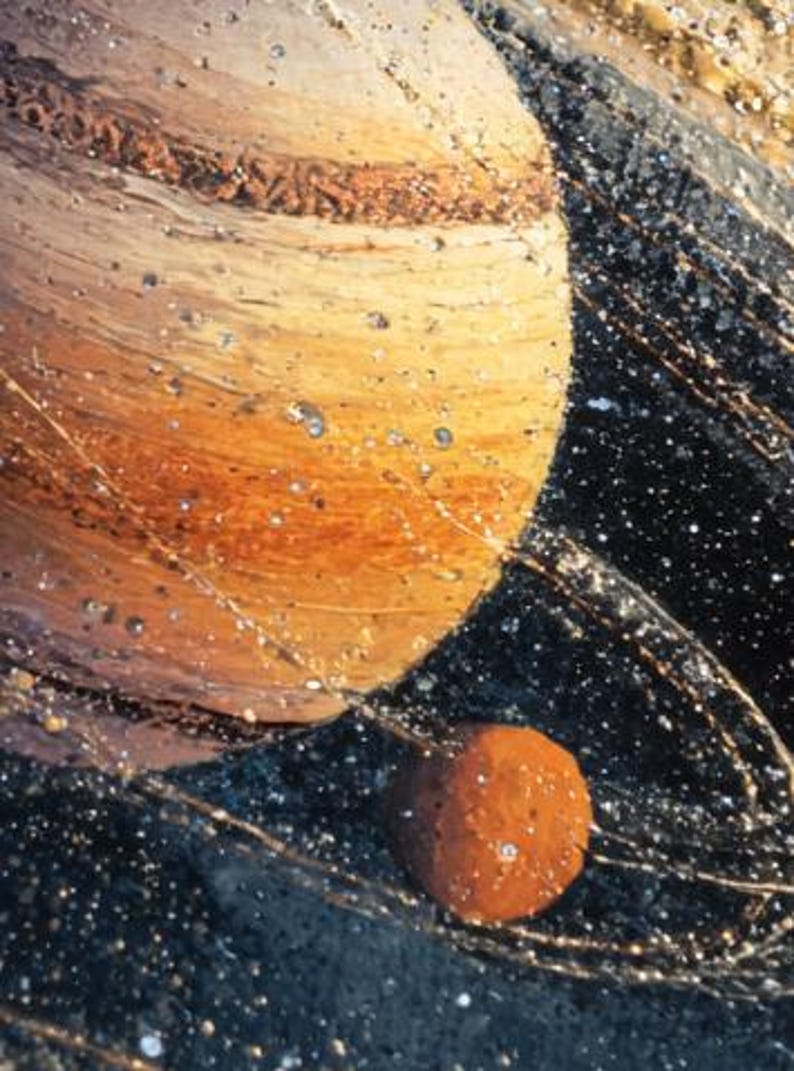 May include: An artistic depiction of celestial bodies, featuring a large planet with bands of brown and tan hues, alongside a smaller, reddish-brown sphere. The background is a dark, speckled space with shimmering lines.