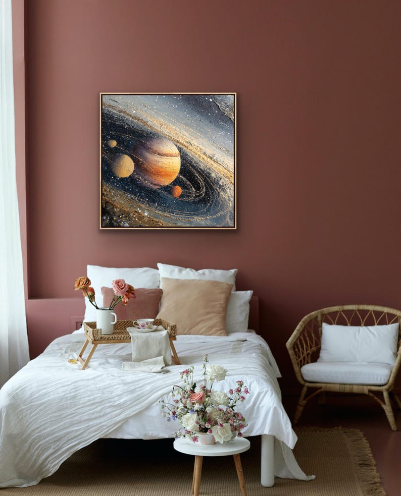 May include: A framed painting of a planet with rings, in shades of orange, brown, and blue, hangs on a maroon wall. The painting is above a bed with white linens, pillows, and a wooden tray with flowers and a cup. A small side table holds a floral arrangement.