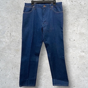 Op de afbeelding: Donkerblauwe denim jeans met een klassiek ontwerp met vijf zakken. De jeans hangen aan een zwarte hanger tegen een gevlekte grijze achtergrond. De jeans hebben een rechte pijp en een knoop- en ritssluiting.
