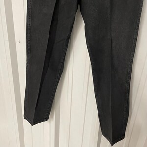 May include: A pair of black denim pants. The pants have a classic five-pocket design with a straight leg cut. The fabric appears to be a medium-weight denim, and the pants have a slightly faded appearance. The pants are suitable for casual wear.