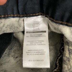 May include: Close-up of a clothing tag with text in English and Spanish. The tag reads "OUTHJEUNESSEJOVEN LARGE GRAND GRANDE SIZE: 12/14" and includes details about the shell material and manufacturing location in Bangladesh.
