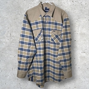 Pode incluir: Uma camisa xadrez de manga comprida com pala e punhos bege. A camisa apresenta um padrão xadrez azul, bege e branco no corpo e é abotoada. A marca "Wrangler" é visível.