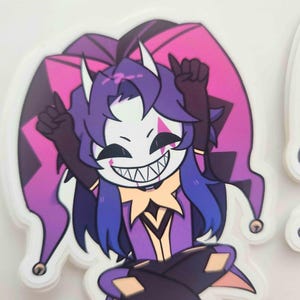 May include: A sticker featuring a cartoon jester character with a white mask, purple hair, and a purple and pink jester hat. The jester is wearing a purple outfit and has a wide, toothy grin. The sticker has a white border.