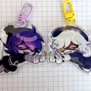 May include: Two acrylic keychains featuring cartoon characters. One has purple hair and a purple clasp, the other has white hair and a yellow clasp. Both characters are in a flying pose with a smiling expression.