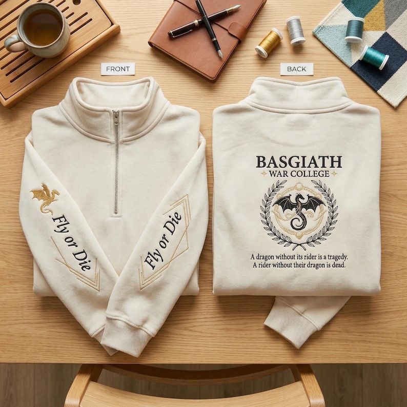 May include: Cream-colored quarter-zip sweatshirt with "Fly or Die" and a gold dragon embroidered on the sleeves. The back features a crest with a dragon and the text "BASGIATH WAR COLLEGE".