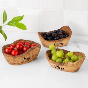 May include: Three wooden olive bowls filled with fresh produce. One bowl holds red tomatoes, another holds black grapes, and the third contains green grapes. Each bowl has a name engraved on it: "Jack", "Cara", and "Rose".