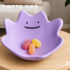 May include: A lavender-colored, Ditto-shaped dish with a smiling face, holding three colorful candies. The dish sits on a light wood table. Text in Chinese characters is visible above the dish.