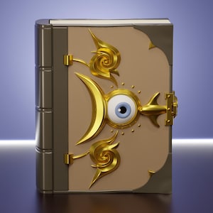 Puede incluir: Un libro de tapa dura con cubierta color canela claro que presenta un emblema central de un ojo dorado rodeado por una luna creciente y dos adornos dorados en espiral. El libro tiene un lomo gris oscuro, esquinas metálicas y un cierre dorado.
