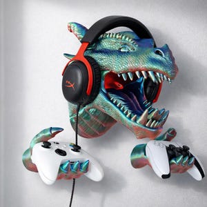 May include: A wall-mounted dragon head sculpture in shades of blue, green, and red, holding a black and red gaming headset, and two white game controllers. The dragon's mouth is open, revealing sharp teeth and a red interior.