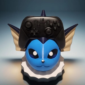 May include: A blue and white Vaporeon-themed Nintendo Switch controller holder. The holder features a blue Vaporeon head with white eyes and a black Nintendo Switch controller resting on top. The holder has a white and blue base.
