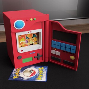 Könnte beinhalten: Ein rotes, 3D-gedrucktes Pokémon-Kartenetui mit einer offenen Tür, die einen Bildschirm mit einem Glurak-Bild zeigt. Das Etui hat Knöpfe und einen blauen Kreis oben, und eine Pokémon-Karte liegt davor.