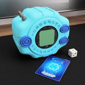 Può includere: Un giocattolo Digivice azzurro con un piccolo schermo, tre pulsanti blu e un'antenna grigia. Un dado bianco e una carta Digimon sono accanto al giocattolo. La carta ha il testo "DIGIMON CARD GAME".