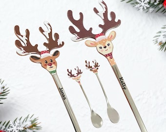 May include: A set of Christmas-themed spoons featuring reindeer designs. The spoons have long, silver handles and decorative reindeer heads with antlers, wearing hats and scarves. The names "Jonas" and "Kelly" are printed on the handles.