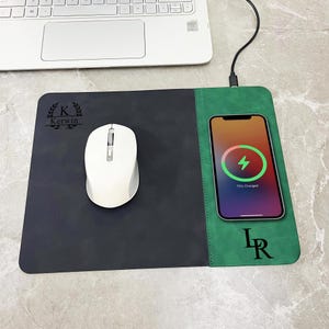 Op de afbeelding: Een zwart en groen draadloos oplaadmuismat met een witte muis en een telefoon die oplaadt. Het telefoonscherm toont een oplaadsymbool en 75% opgeladen. De mat heeft de tekst "Kerwin" en "LR".