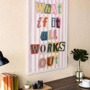 May include: A framed print with a pink and white striped background and the text "What if it all works out" in colorful, cut-out letters.