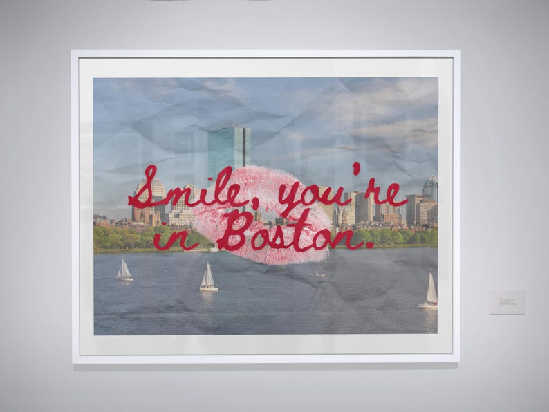 May include: Framed art print featuring a Boston skyline with a red lipstick kiss and the text "Smile, you're in Boston." The image includes sailboats on the water and a cloudy sky.