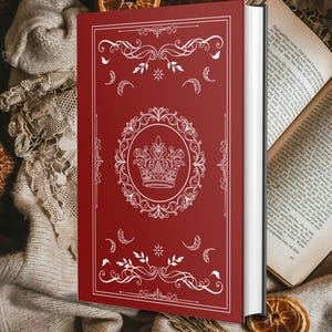 May include: A red hardcover book with a white decorative design, including a crown and flourishes. The book is open, revealing the pages. A dried orange slice is in the background. The book's cover has a detailed design.